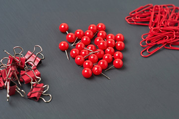Heaps of many binders, clips and pins for paper on dark concrete desk in office, school or home....