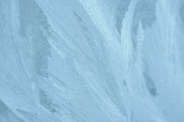 Frosty patterns on the window in winter. Natural abstract background of blue color