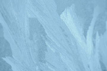 Frosty patterns on the window in winter. Natural abstract background of blue color