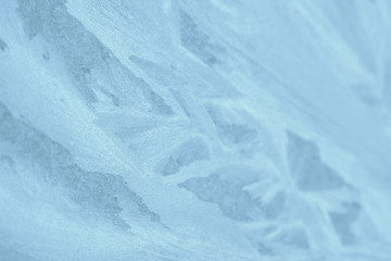 Frosty patterns on the window in winter. Natural abstract background of blue color