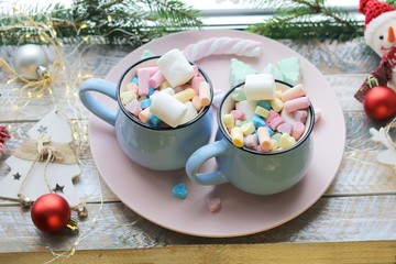 Two cups with a drink and marshmallows, Christmas decor, illuminations on a wooden windowsill, the concept of home comfort, winter holidays