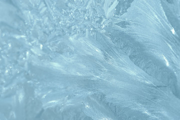 Frosty patterns on the window in winter. Natural abstract background of blue color