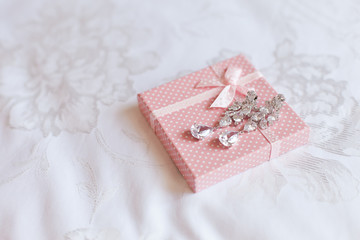 Two wedding eardrops on a pink gift box. Bridal wedding accessories