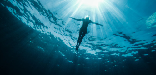 Woman floating in the sea and rays of light piercing through