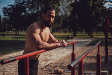 Fototapeta premium Macho athlete resting on the outdoor gym bar