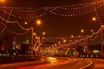 the dam and the road on it with passing cars at the new year's illumination, filmed on a December evening in Cheboksary