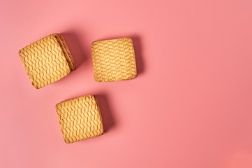 Three heaps of whole square cookies lies on pink desk on kitchen. Space for text. Top view
