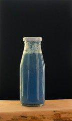 blue matcha and blueberry smoothie drink in glass bottle on dark background. still life