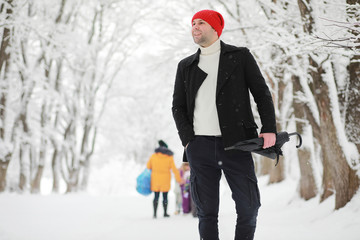 A man on a walk in the park. Young man with in the winter snowfall.