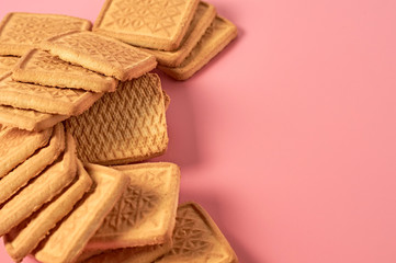 Scattered whole square cookies on pink desk on kitchen. Space for text