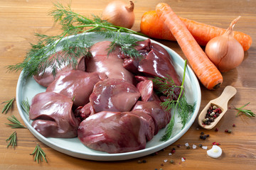 Fresh raw turkey liver with fresh vegetables on wooden background