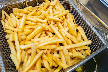 French fries on a special grid. Industrial deep fryer. Deep-fried cooking. Frying products in hot...