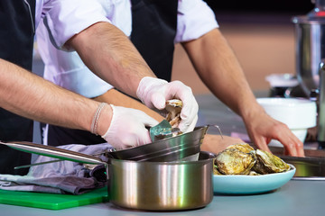 The cook cleans the oysters. Seafood dish. Fish restaurant. Cooking mussels. Seafood on the table in the kitchen of the restaurant.