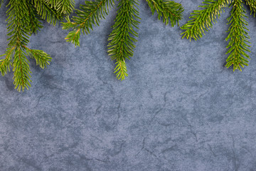 Christmas motif, texture, background with branches of a Nordmann fir at the top on a dark grey blue marbled  background with free space for text.