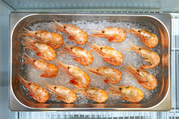 Shrimp are on the ice. Seafood in a shop window. Sale of seafood. Refrigeration equipment. The counter of the fish shop shrimp. Fish trade.