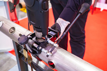 Metalworking. Punching press for pipes. The machine punches holes in the metal. Equipment of Metalworking production. Locksmith working on the machine for punching holes in the pipe.