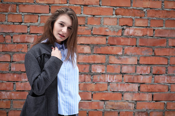 Young beautiful girl near red brick wall posing
