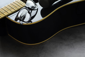 Guitar and accessories on a stone background. Desk musician, headphones, microphone.