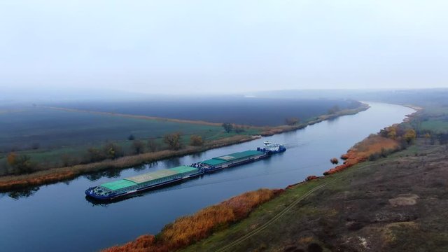 Barge towing two barge loaded by grain on the river Southern Bug. Calm water without wind, fog weather, visibility restricted.