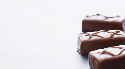Chocolate bars on a black background in backlight. Chocolate with filling. Sweet sweets for snack and tea.