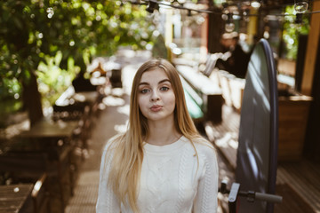 girl stares confusedly in front of herself while standing in a street cafe