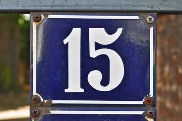 A house number plaque, showing the white coloured number fifteen (15)