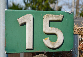 A house number plaque, showing the white coloured number fifteen (15)