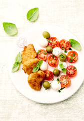 Chicken Nuggets with mozzarella cheese, cherry tomatoes, green olives and fresh basil. Bright background. Top view. 