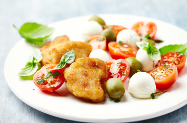 Chicken Nuggets with mozzarella cheese, cherry tomatoes, green olives and fresh basil. Bright background. Close up. 