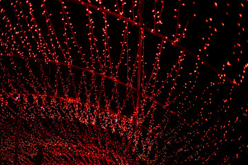 A wave of red LEDs in the dark. Abstract bright red background built on LED strips. City lighting in the park for the New Year holidays. Christmas decoration.