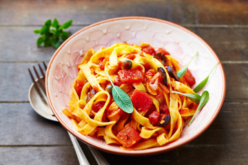 Tagliatelle pasta on brown wooden background.