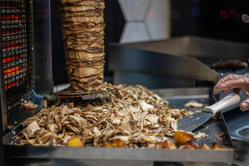 Tasty meat on a spit. The cook is preparing shawarma. The meat is fried on the stove. Folk cuisine of the east.