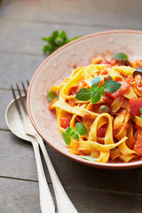 Tagliatelle pasta on brown wooden background. Close up. 