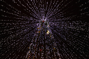 Obraz premium Christmas tree decorated with bright lamps. Big tree delivered for christmas. A lot of LEDs on the tree. Design of park illumination on holidays. Elegant city lighting.