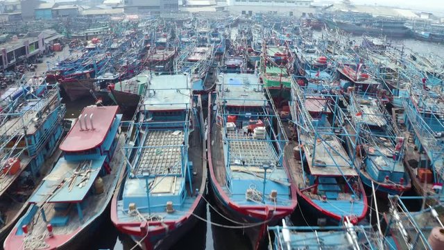 JAKARTA, Indonesia - December 10, 2019: Aerial landscape of traditional fishing boats in Muara Angke harbor. Shot in 4k resolution from a drone flying forwards