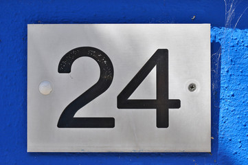 A house number plaque, showing the number twenty four (24)