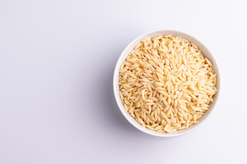 Orzo pasta, isolated on white background. Italian orzo pasta shaped like grains of rice, copy space, soft light