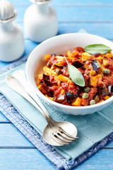 Penne pasta with vegetable sauce and fresh herbst. Bright background. 