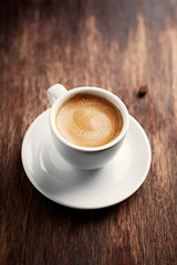 Cup of coffee on brown wooden background. 