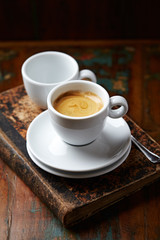Cup of coffee and old book on rustic background. 