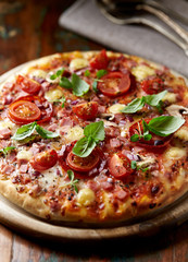 Pizza with cherry tomatoes and fresh herbs. Home made food. Concept for a tasty and hearty meal. Brown wooden background. 