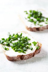 Tasty sandwiches with cream cheese and chive. Bright wooden background. Close up. 
