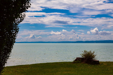 Background image - Lake Balaton in Hungary against a cloudy sky. In the foreground is a stump from...
