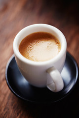 Cup of coffee on brown wooden background. Close up.