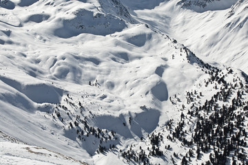 Fototapeta na wymiar Blick von der Axamer Lizum Tirol in den Alpen auf die schneebedeckten Berge und Tiefschneehang bei Neuschnee im Winter. Lawinengefahr. Wald