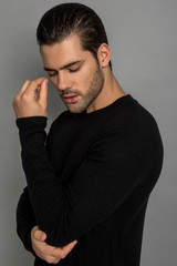 Muscle strong beautiful stripped male model in black jamper and black trousers on grey isolated font background