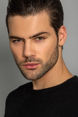 Fototapeta premium Muscle strong beautiful stripped male model in black jamper and black trousers on grey isolated font background