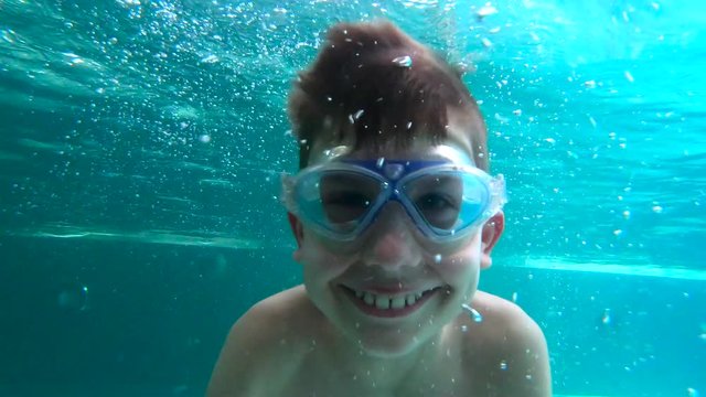 Young boy is diving happily underwater at indoor swimming pool