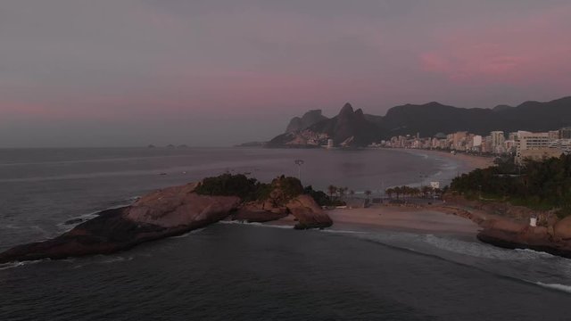Aerial steady shot showing the ocean waves that come in on Devils beach and Arpoador rock in Rio de Janeiro with Ipanema and Leblon beaches in the background at early morning sunrise