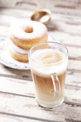 Latte coffee in glass. Tasty donuts in background. 